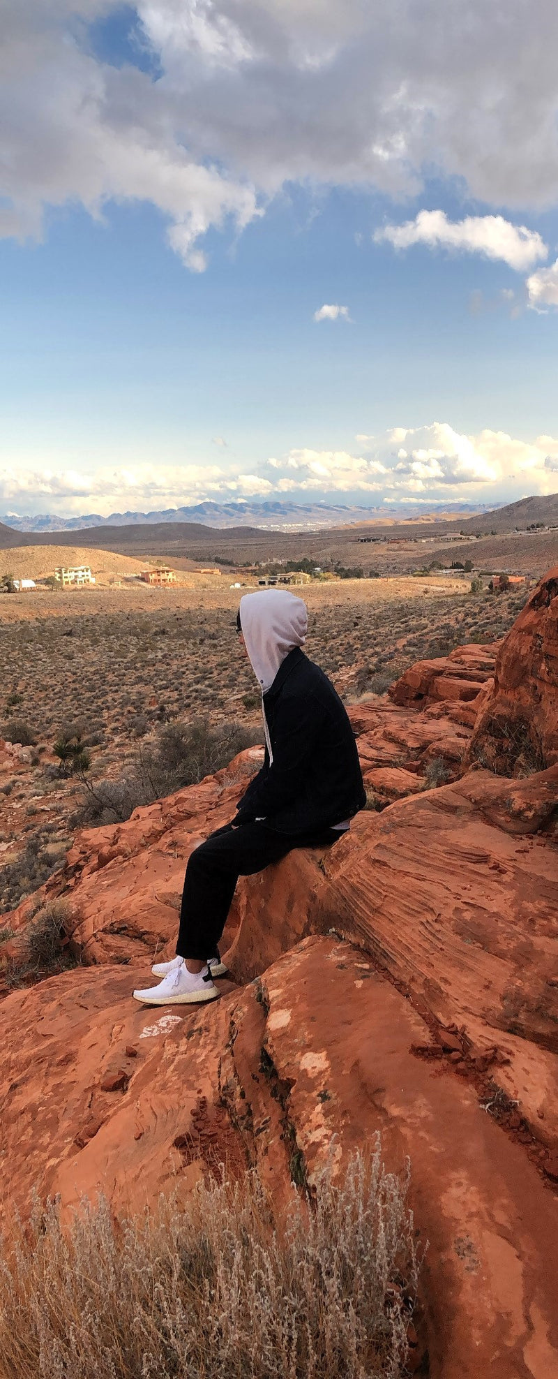 Person sitting on a rocky outcrop with a scenic landscape in the background