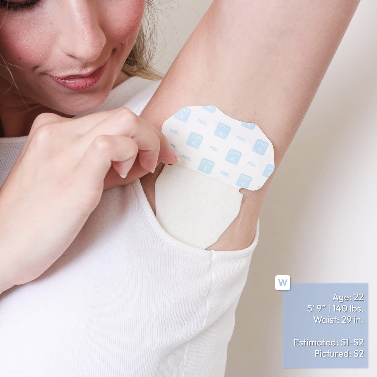 A close-up of a woman wearing a white tank top peeling the top half of a Paper Outer Liner of an underarm adhesive patch fully applied to her armpit. A small blue informational label appears in the lower right corner with text about size and fit.