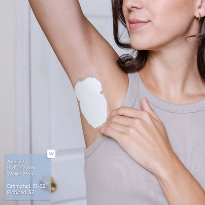 A woman wearing a light gray ribbed tank top shows an underarm patch application on her armpit. The image includes a size reference label in the bottom-left corner with text reading: Age: 22, 5'8" 125 pounds, Waist: 26 inches, Estimated S1-S2, Pictured S2.