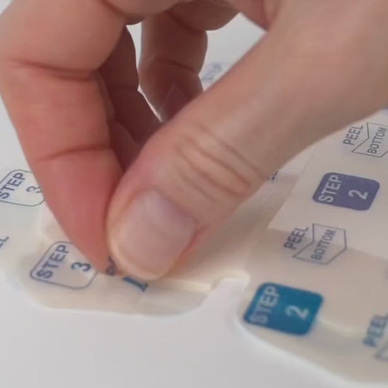 Peeling two quadrants of the clear inner liner slowly back along the adhesive border.